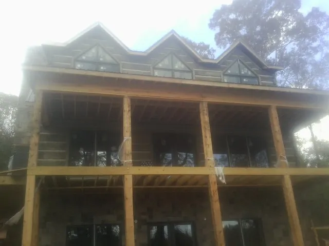 Dormers and porch framing on a large log home under construction — Roof Coating work by our crew in Williamsburg